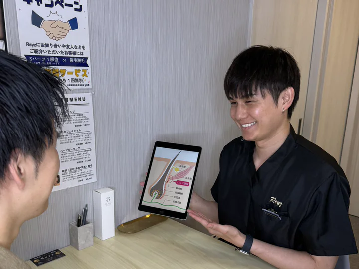 Reyzの男性スタッフがタブレットを見せながらカウンセリングしている様子